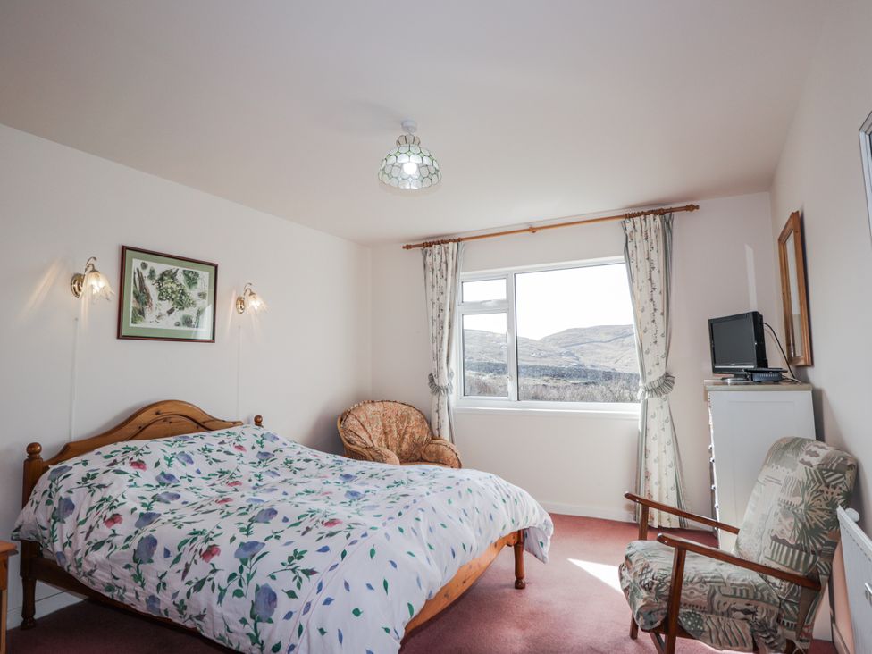 A bedroom with a bed and chair at An Grianan Kinlochbervie