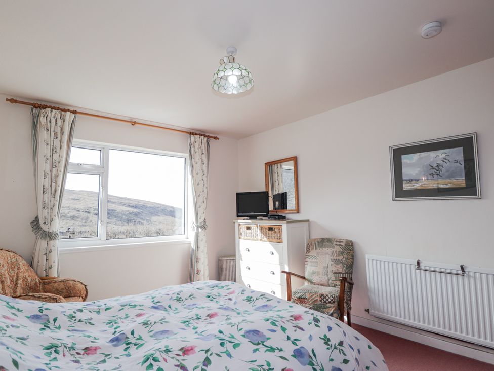 A bedroom with a bed, television, and window at An Grianan in Kinlochbervie