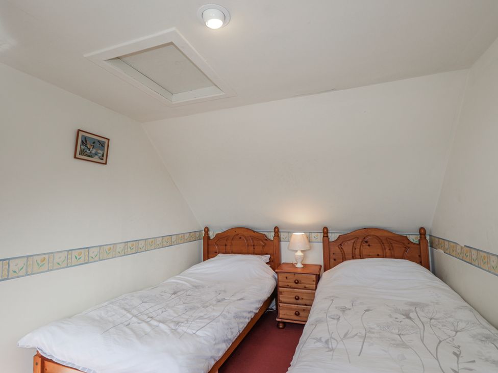 A bedroom with two beds and a bedside table at An Grianan in Kinlochbervie