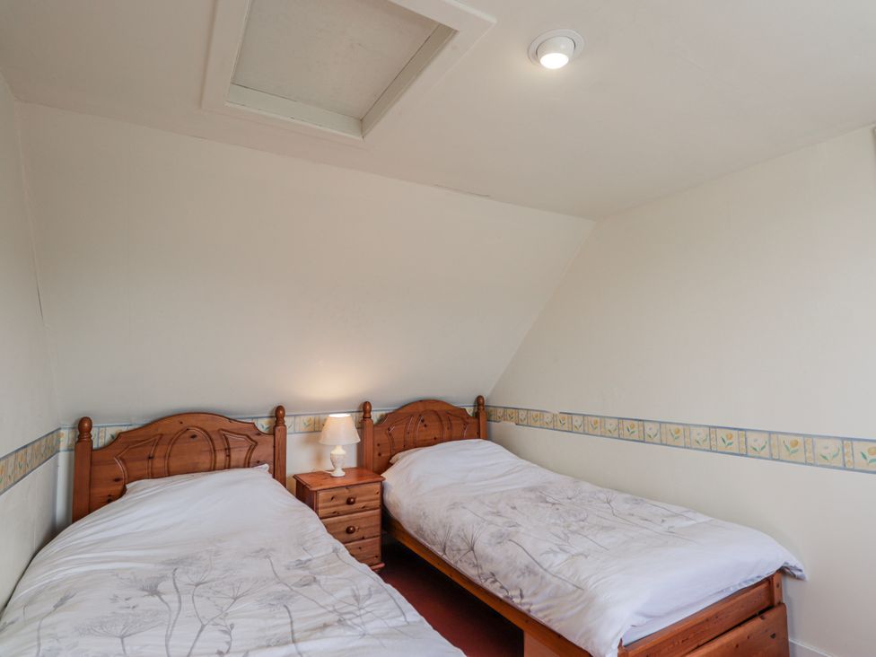 A bedroom with twin beds and a nightstand at An Grianan Kinlochbervie