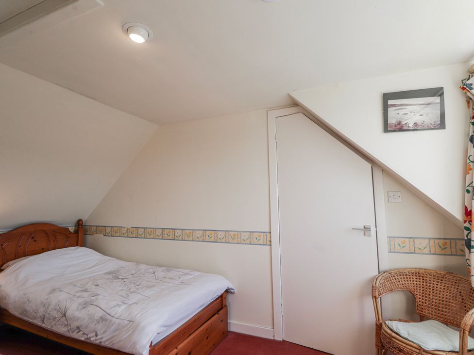 A bedroom with a bed and a chair at An Grianan in Kinlochbervie