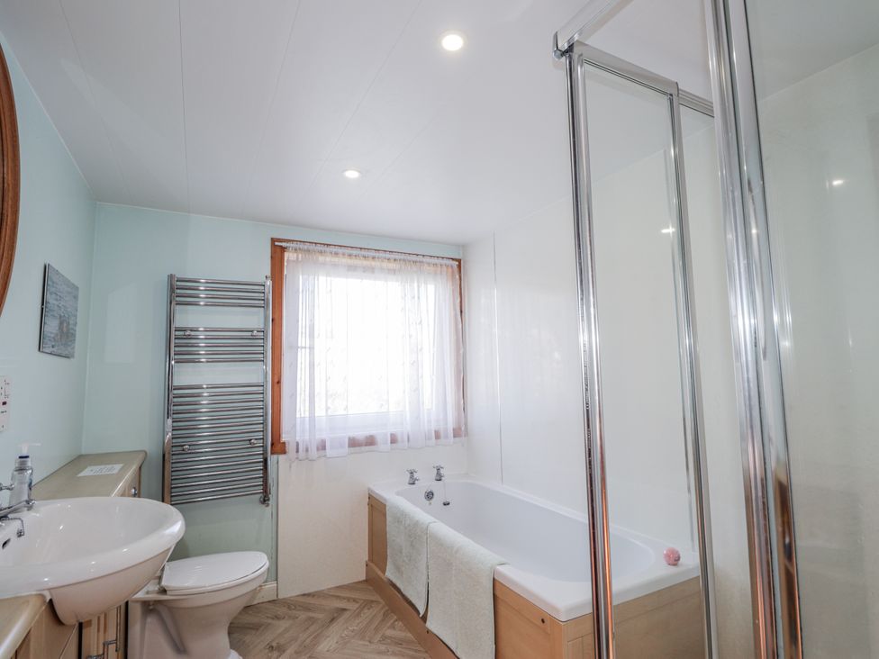A bathroom with a bathtub, sink, and shower stall at An Grianan in Kinlochbervie