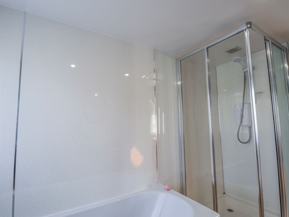A bathroom with a bathtub and shower enclosure at An Grianan in Kinlochbervie