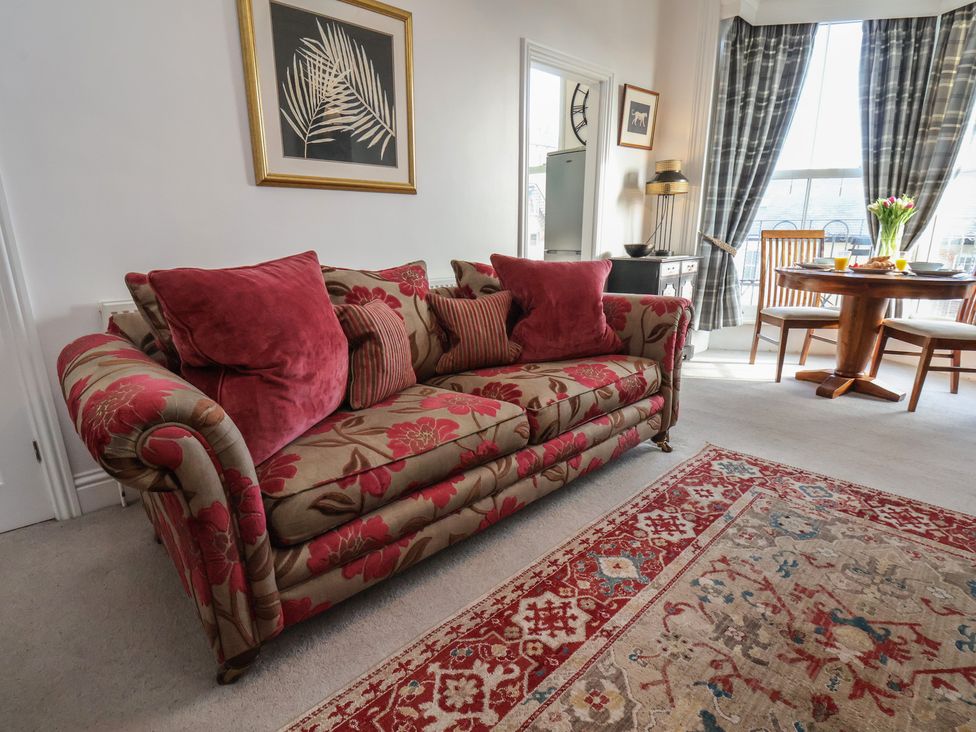 A living room with a floral sofa and dining table at Masons Place in Whitby