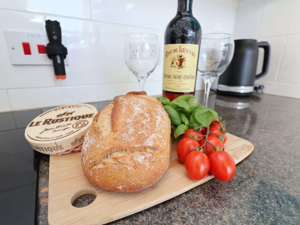 A kitchen countertop with bread, cheese, wine, tomatoes and glasses at Masons Place Whitby