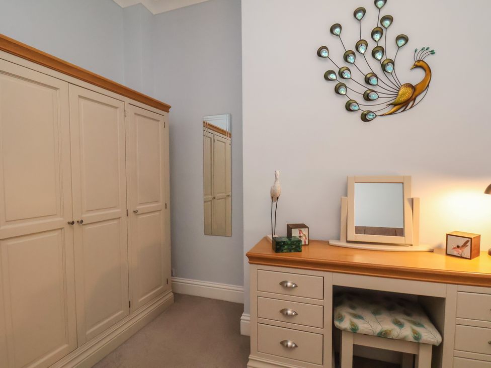A bedroom with a wardrobe, desk, and mirror at Masons Place in Whitby