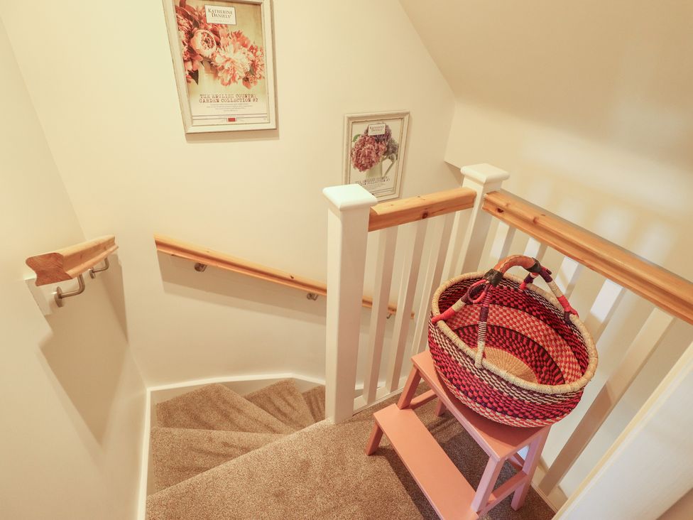 A staircase with railing and a basket on a stool at 4 Eve Street in Louth