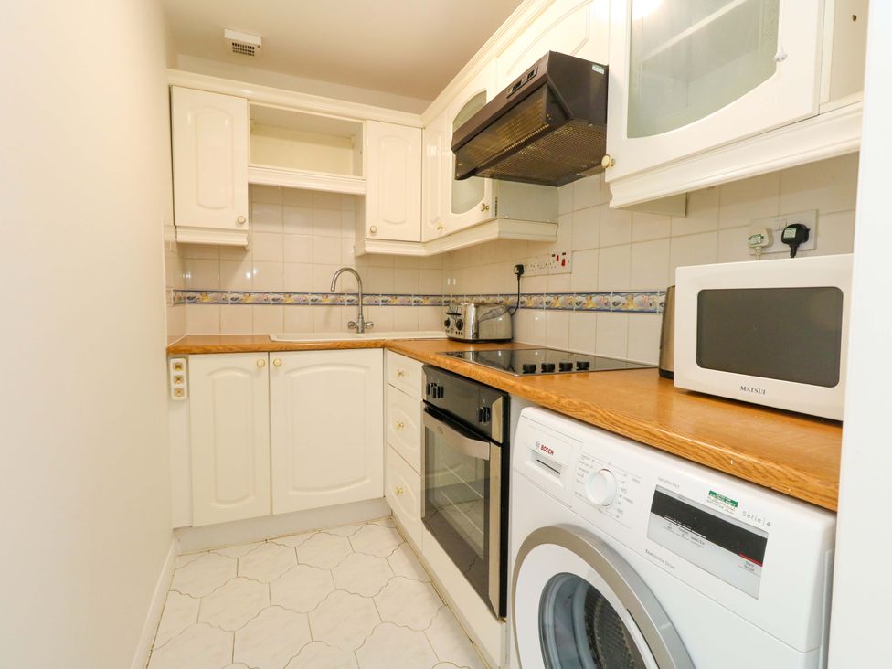 A kitchen with cupboards, sink, oven, microwave, and washing machine at 32 Bowleaze Coveway Weymouth