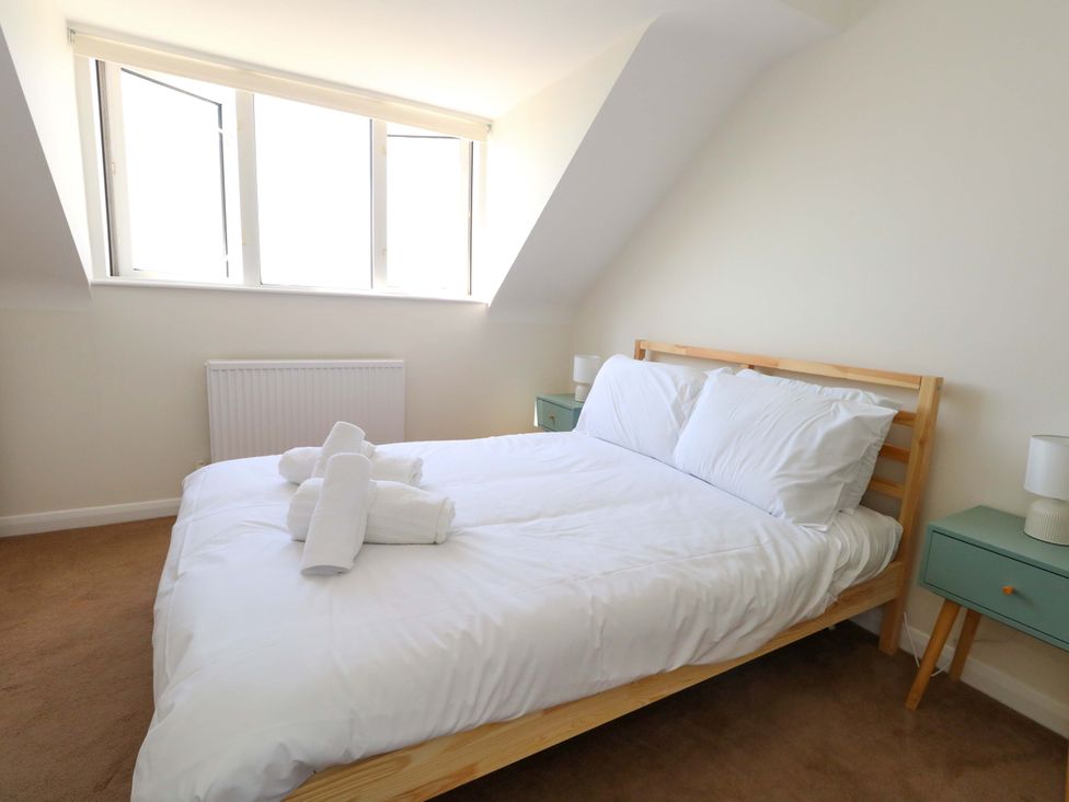 A bedroom with a bed and two windows at 32 Bowleaze Coveway in Weymouth