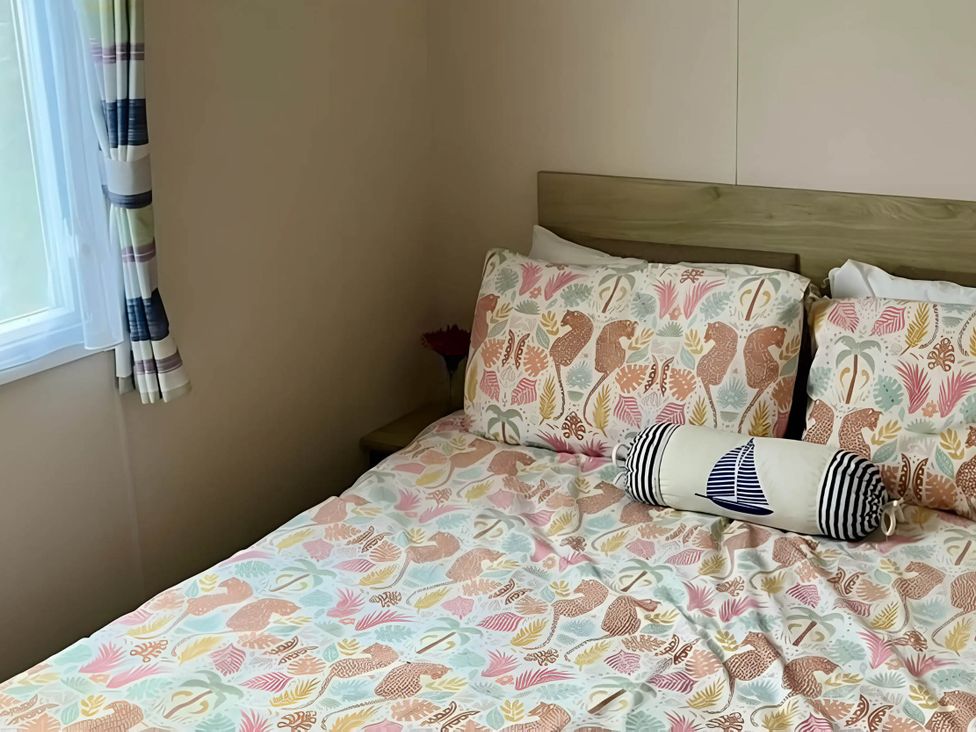 A bedroom with a bed and window at Static Caravan Hoburne Devon Bay in Paignton