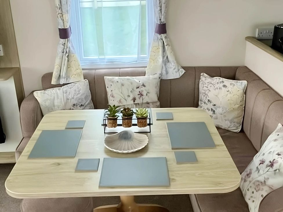 A dining area with a table and cushions at Static Caravan Hoburne Devon Bay, Paignton