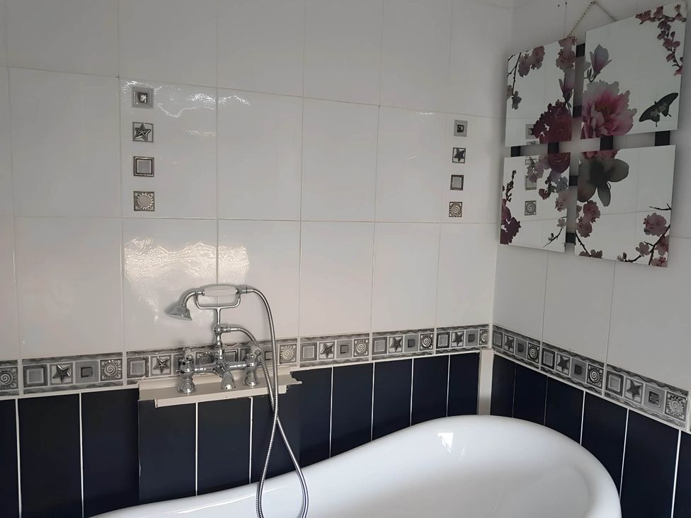 A bathroom with a bathtub and wall art at House - Sleeps 7 - Garden - Pets Ok - Parking in Torquay