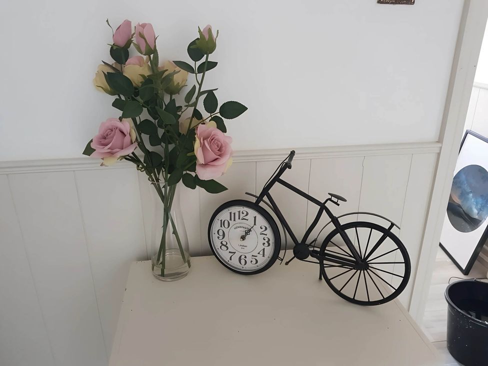 A decorative arrangement with roses, a clock, and a bicycle at House - Sleeps 7 - Garden - Pets Ok - Parking Torquay