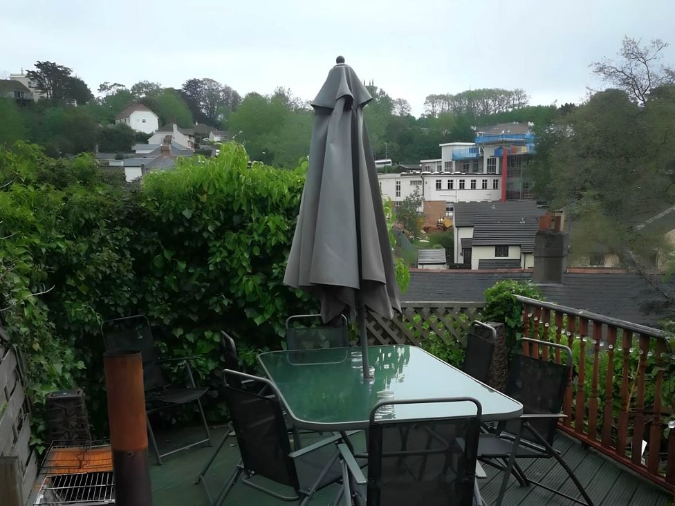 A garden with a table and chairs under an umbrella at House - Sleeps 7 - Garden - Pets Ok - Parking in Torquay