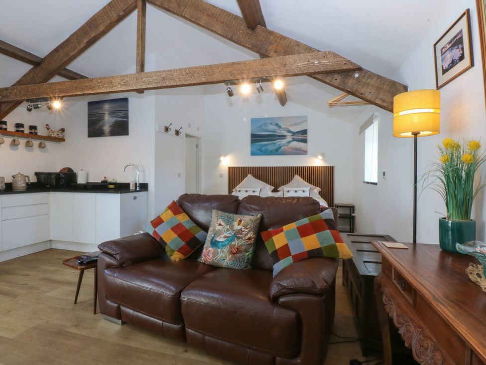 A living room with a sofa and kitchen area at Studio near Bontnewydd