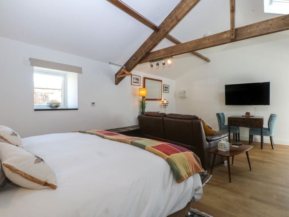 A studio with bed, sofa, table, and television at Studio near Bontnewydd