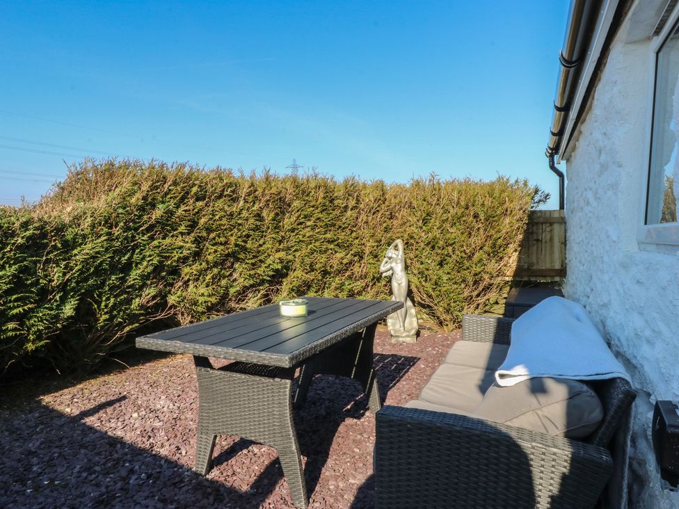 A garden with a table, couch, and statue at Studio near Bontnewydd