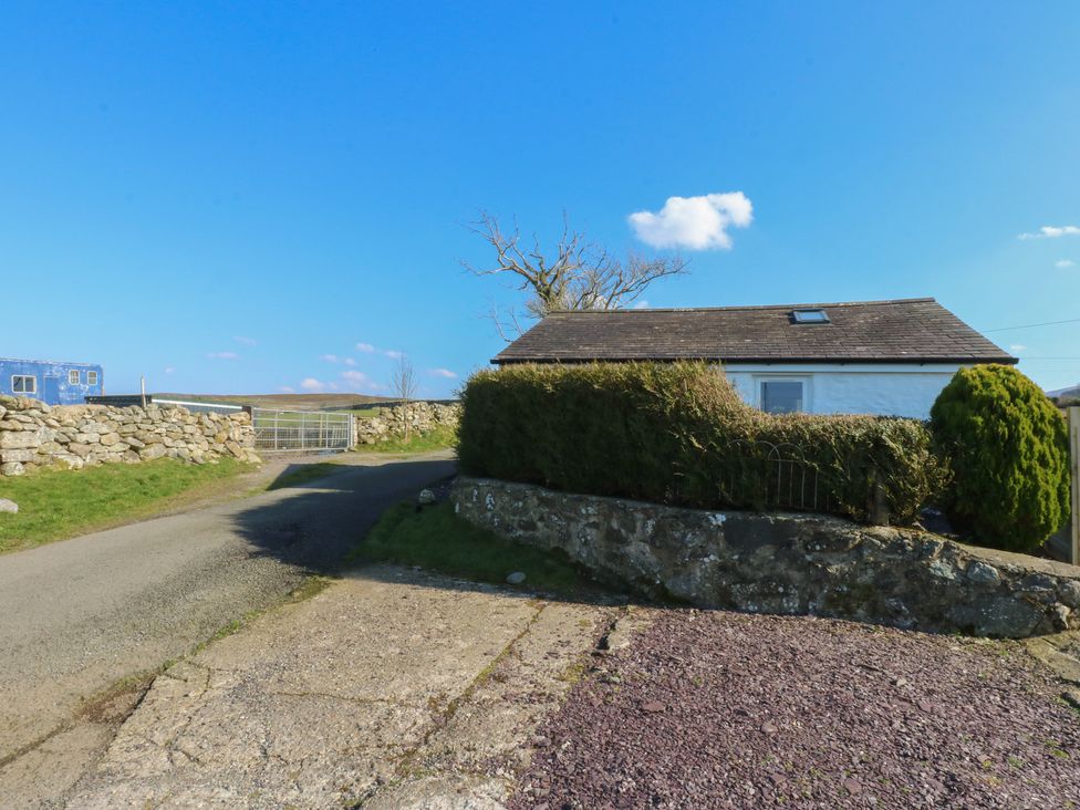 A house along a road with a stone wall and hedge at Studio near Bontnewydd