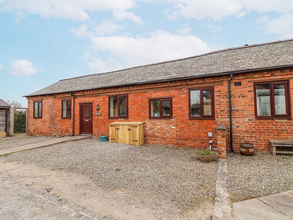A brick exterior of a cottage with windows and a wooden storage at Elwy Cottage in St. Asaph