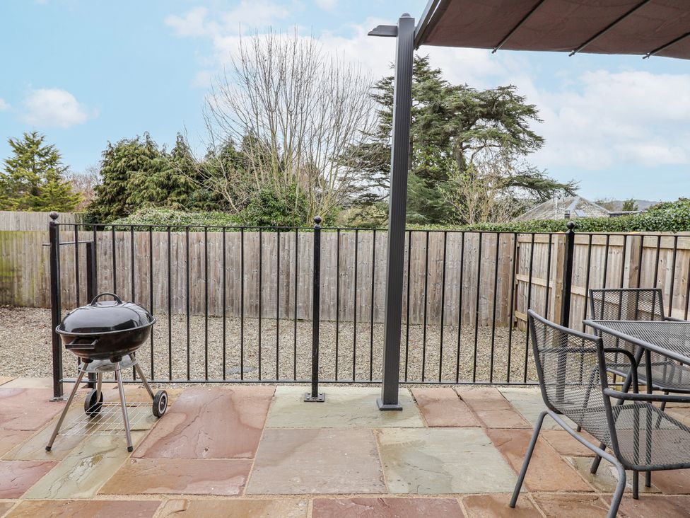 An outdoor area with a grill and table with chairs at Elwy Cottage, St. Asaph