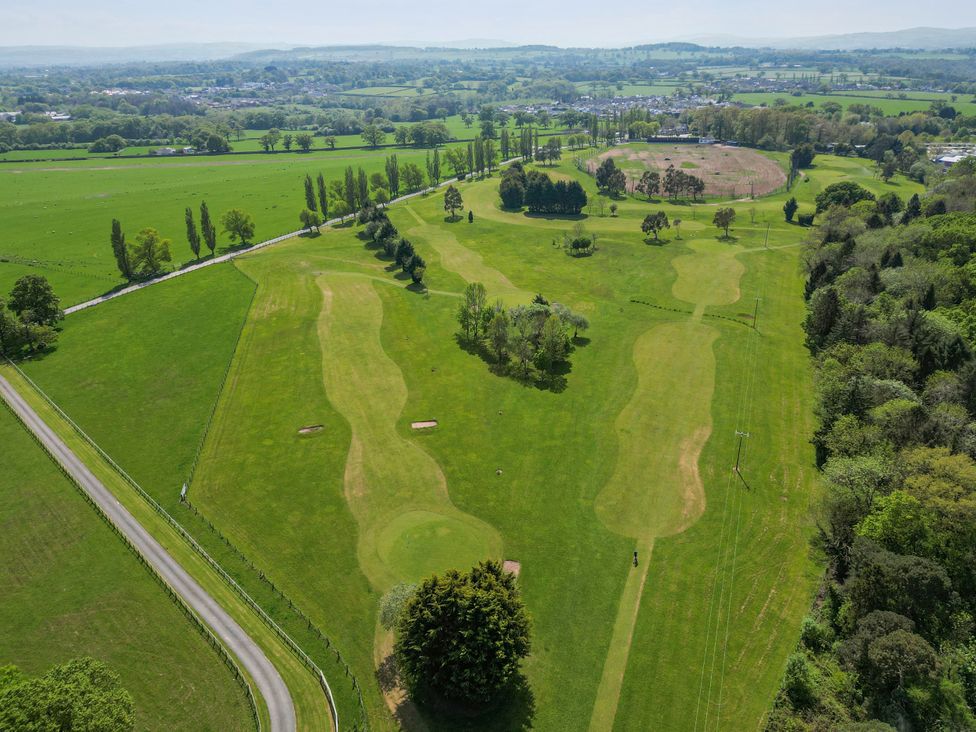 An aerial view of a golf course with fairways and adjacent trees at Elwy Cottage St Asaph