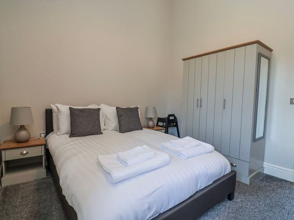 A bedroom with a bed, bedside tables, lamps and a wardrobe at Elwy Cottage St Asaph