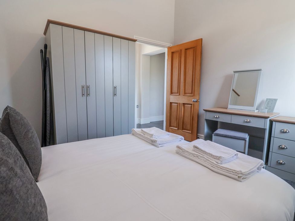 A bedroom with a bed, wardrobe, and mirror at Elwy Cottage in St Asaph