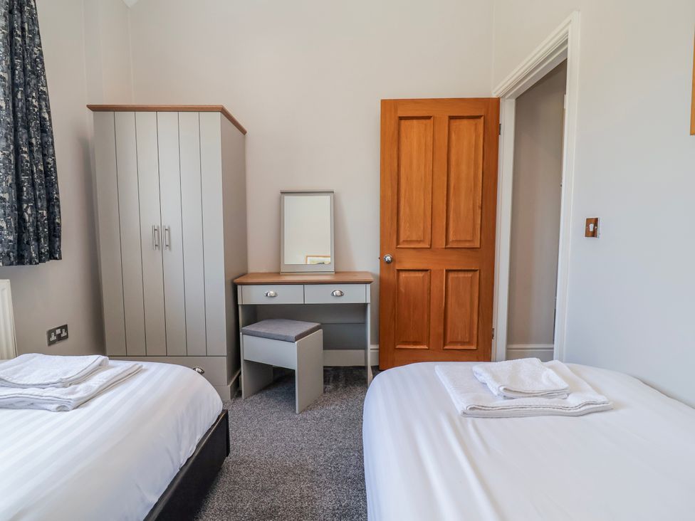 A bedroom with two beds, wardrobe, mirror, and desk at Elwy Cottage in St Asaph