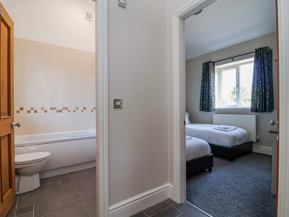 A bathroom with a bath tub and adjoining bedroom at Elwy Cottage St Asaph