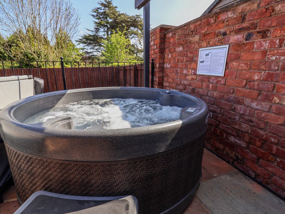A hot tub with water and a sign in an outdoor area at Elwy Cottage St Asaph