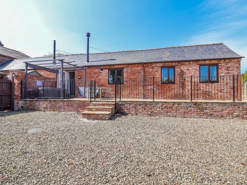 An outdoor area with a brick building and seating at Elwy Cottage in St Asaph