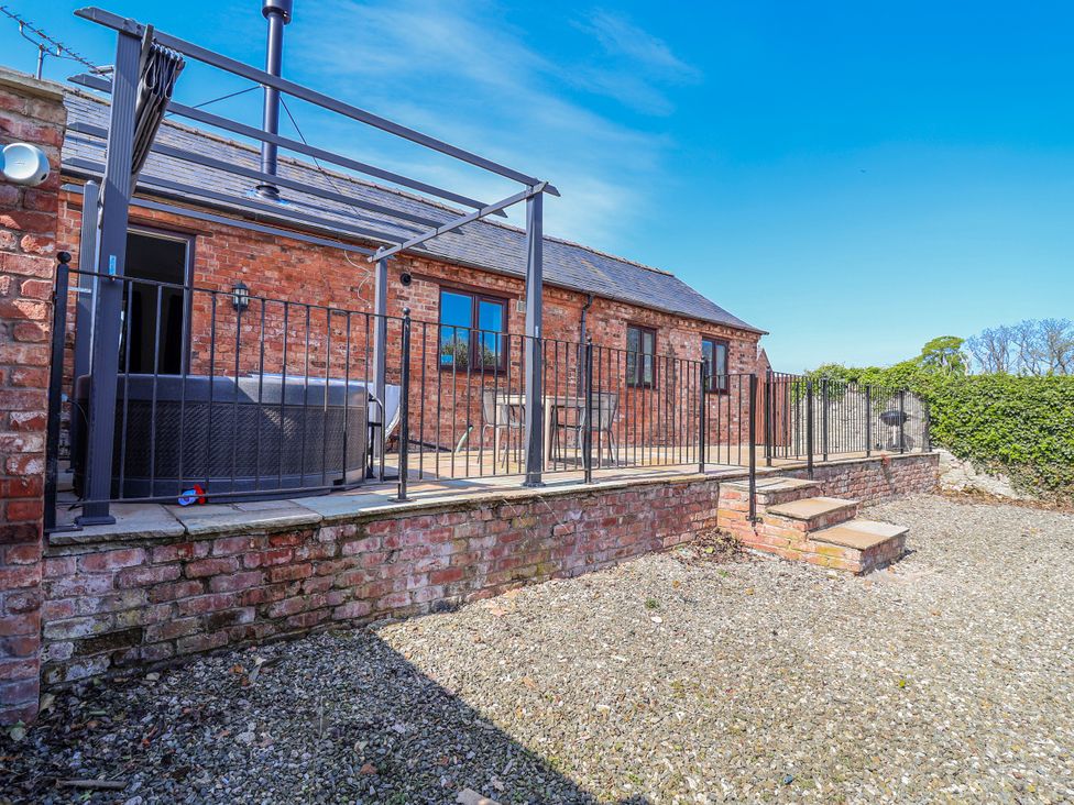 An outdoor area with a hot tub and furniture at Elwy Cottage in St Asaph