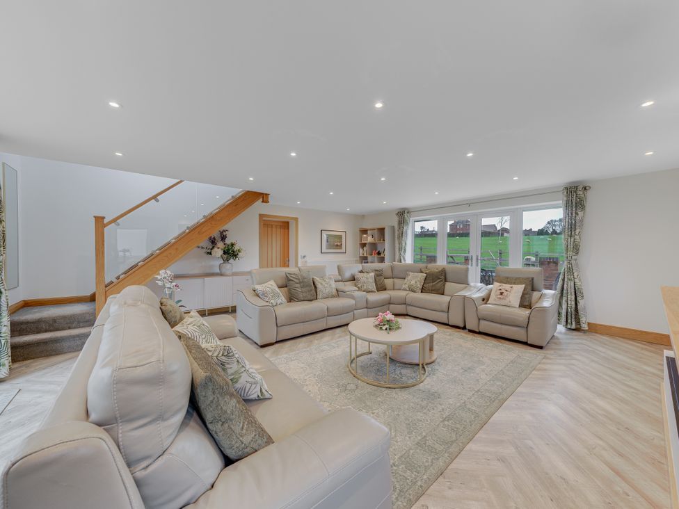 A living room with a sectional sofa and a round table at Greenacres Farm Harriseahead near Mow Cop