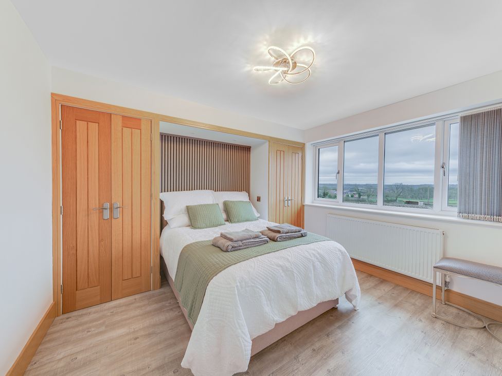 A bedroom with a bed and two windows at Greenacres Farm near Mow Cop