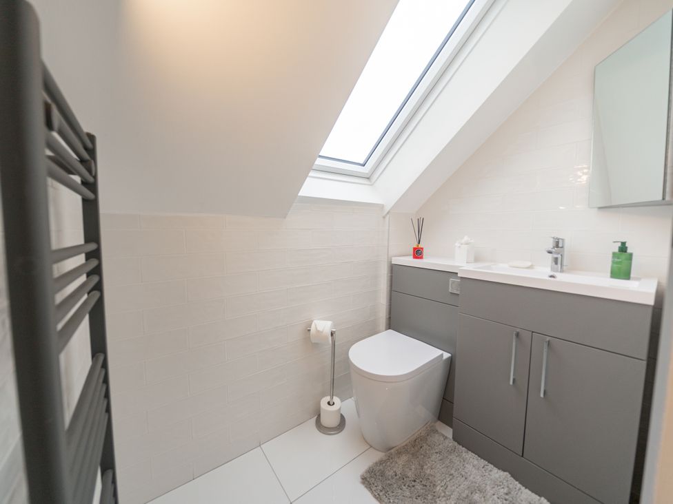 A bathroom with a toilet, sink and storage cabinet at Greenacres Farm Harriseahead near Mow Cop