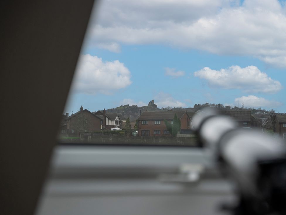 A view from inside through a window with houses and a hill at Greenacres Farm Harriseahead near Mow Cop