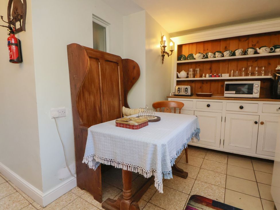 A kitchen with a table and chairs along with shelves storing dishes at The Jewel In The Crown near Biddulph Moor