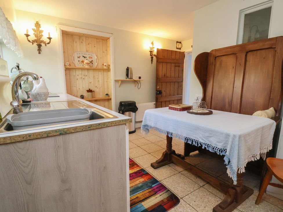 A kitchen with a sink and wooden table at The Jewel In The Crown near Biddulph Moor