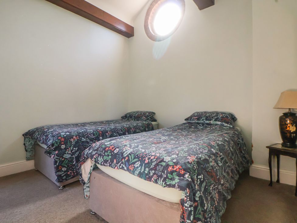 A bedroom with two single beds and a lamp at The Jewel In The Crown near Biddulph Moor