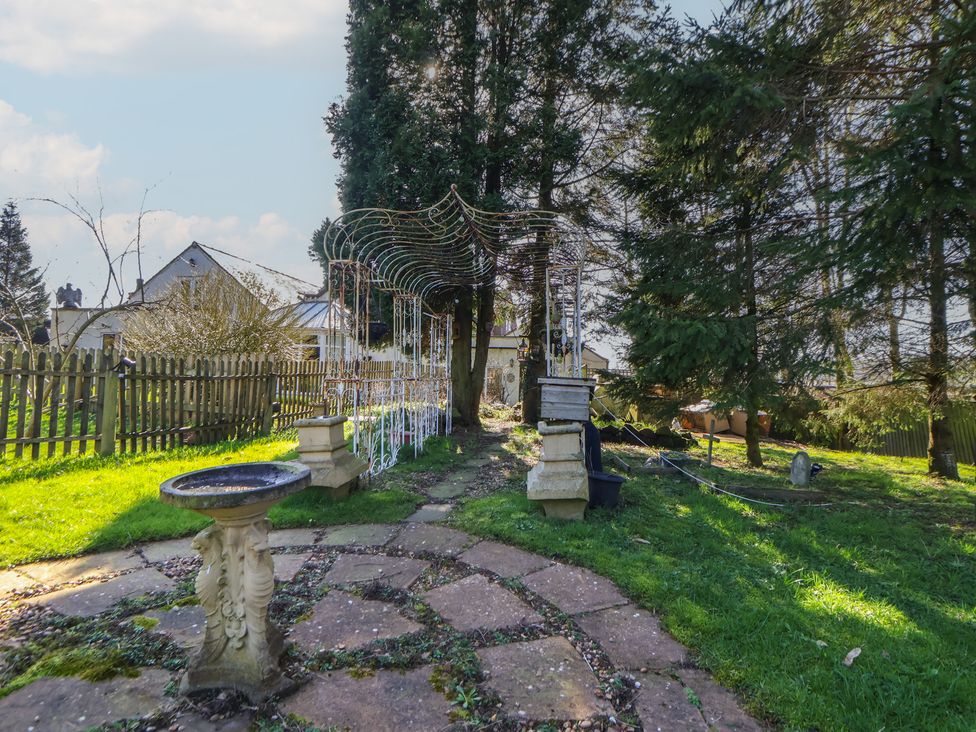 A garden with a birdbath and a stone pathway at The Jewel In The Crown near Biddulph Moor