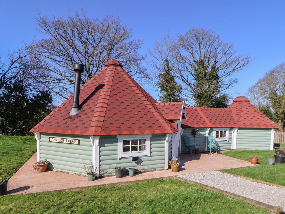 An outdoor view of a log cabin with a chimney at Antlers Lodge in Biddulph Moor