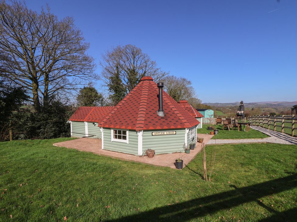 A cottage with a red roof in a grassy area at Antlers Lodge in Biddulph Moor