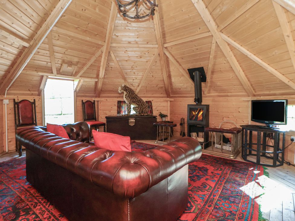 A snug with a sofa, fireplace, and television at Antlers Lodge, Biddulph Moor