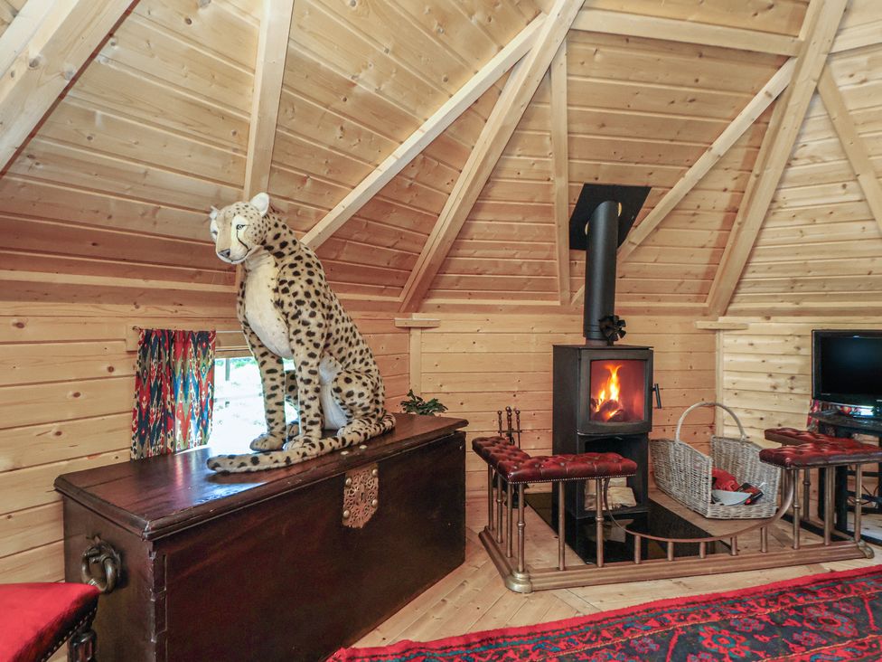 A living room featuring a wood stove and a stuffed leopard at Antlers Lodge in Biddulph Moor