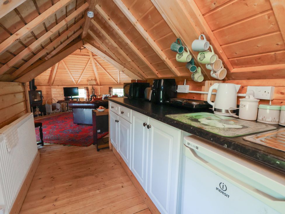 A kitchen with appliances and mugs in hooks at Antlers Lodge in Biddulph Moor
