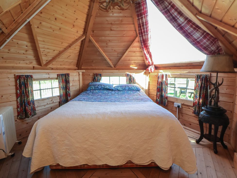 A bedroom with a bed and windows at Antlers Lodge in Biddulph Moor