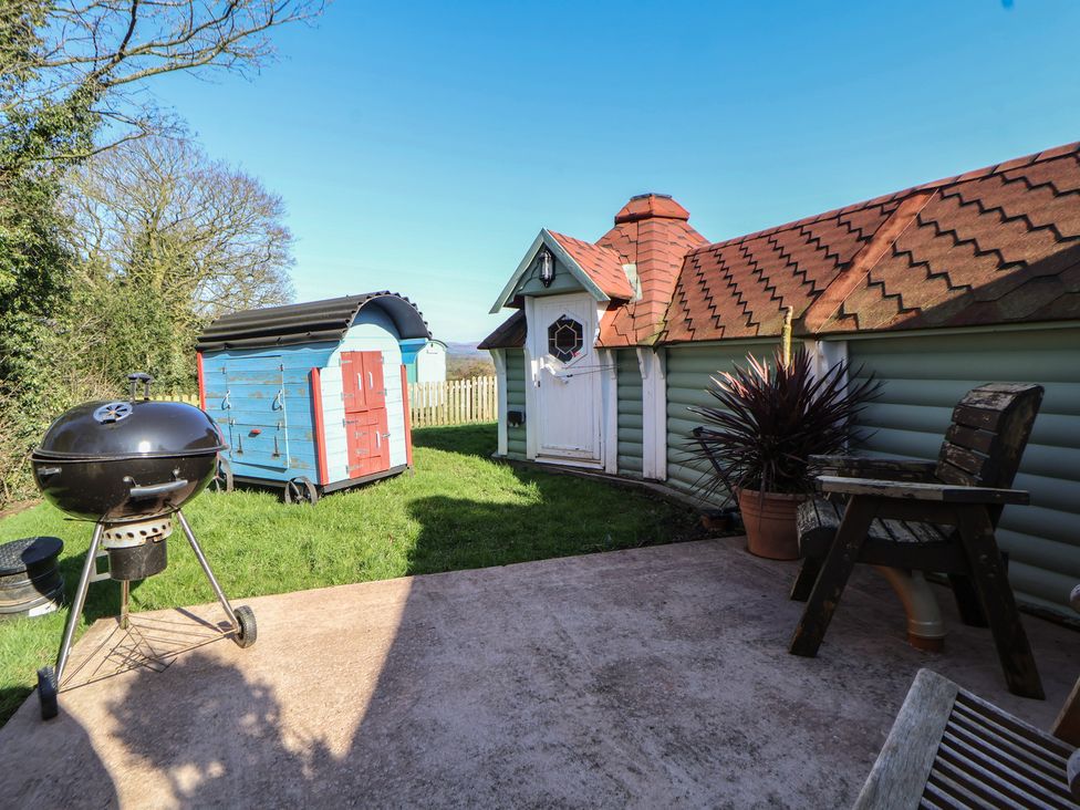 A garden with a barbecue grill and small structures at Antlers Lodge in Biddulph Moor
