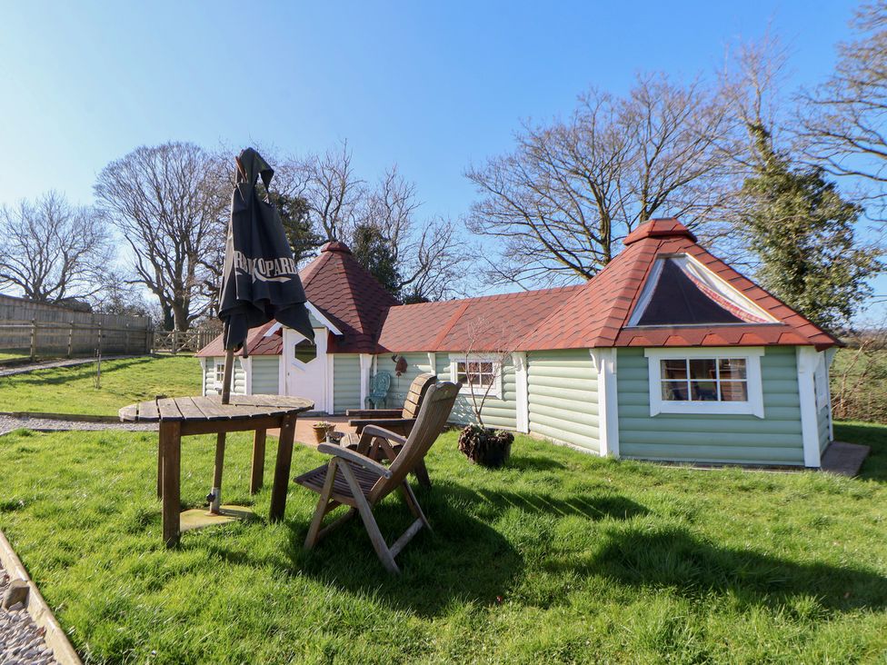 A cabin with a table and chair in an outdoor area at Antlers Lodge Biddulph Moor