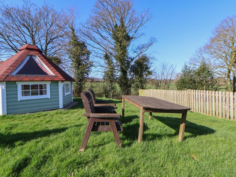 A garden with a table and bench beside a shed at Antlers Lodge in Biddulph Moor