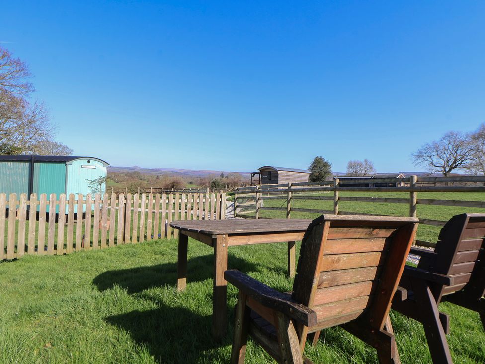 A garden with wooden furniture and mobile homes at Antlers Lodge in Biddulph Moor